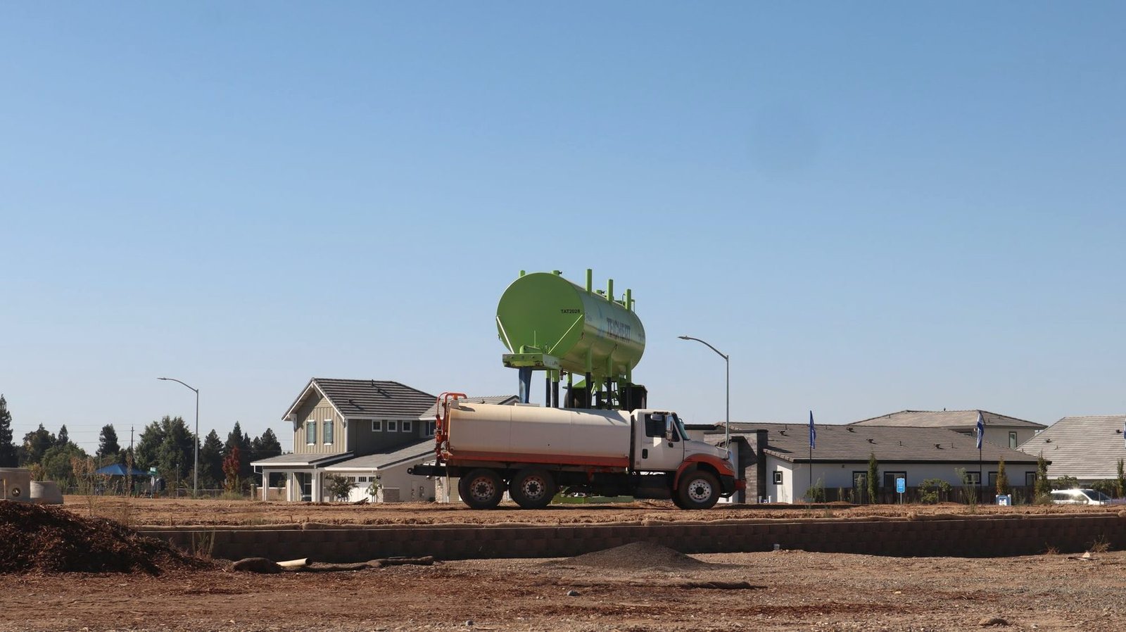 A tanker truck parked on the access road of a cleared construction plot.